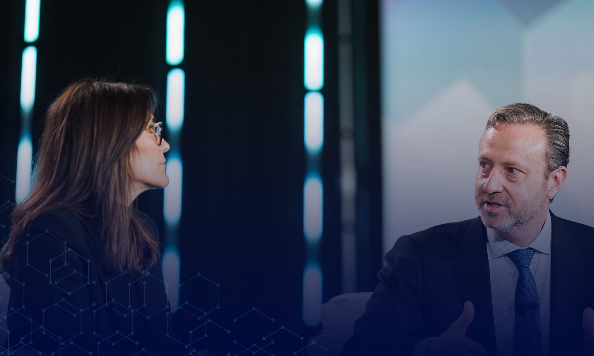 Two professionals discussing AI technology on a conference stage