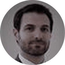 A blurry, professional headshot of a man with short dark hair, a beard, and wearing a suit, pictured against a plain background—suggesting he may be one of the matrix radiologists.