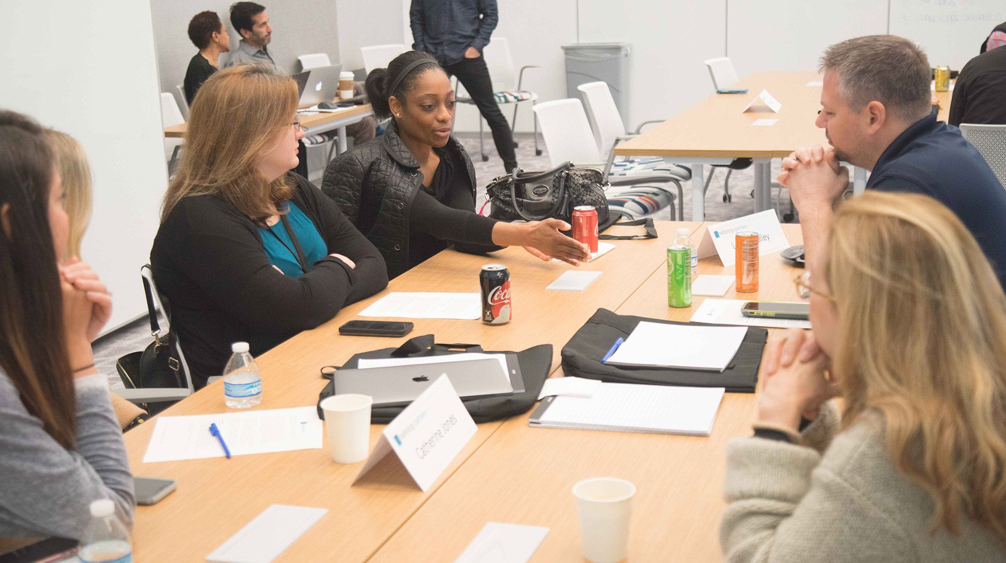 group of 5 people conversing at a work table