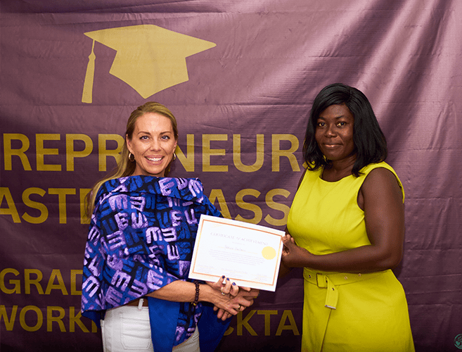 two women exchanging a handshake and an award.