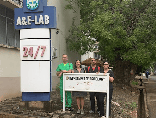 4 people posing behind a department of radiology sign